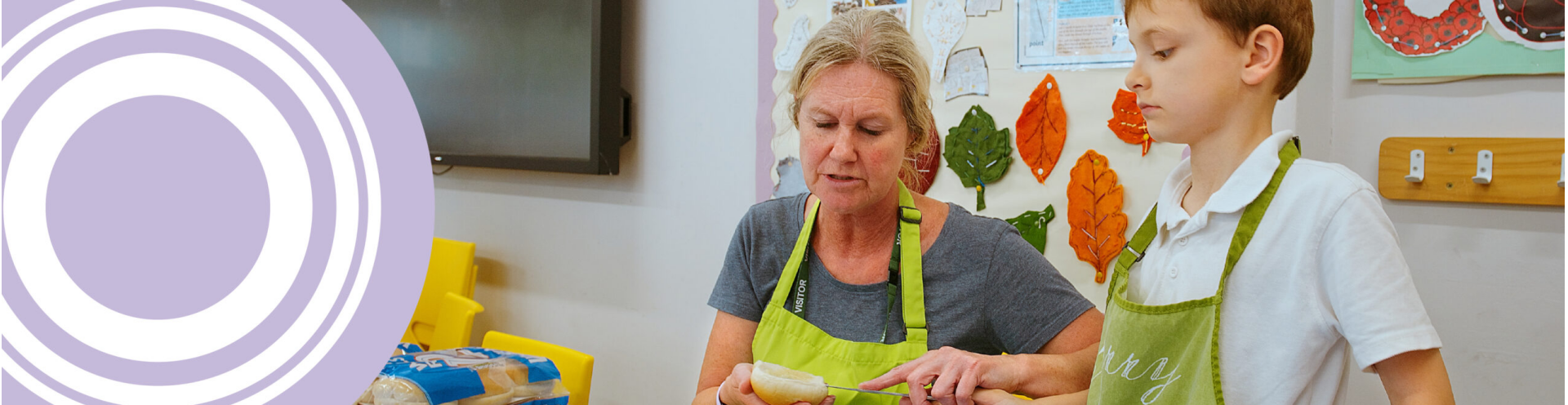 Woman helping young boy make sandwiches